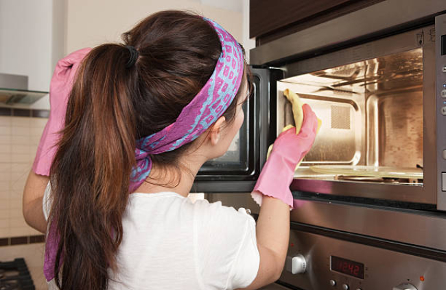 Girl cleaning oven in the kitche