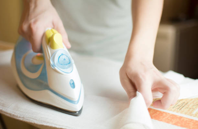 Closeup image of woman hand ironing baby diapers with space for tex