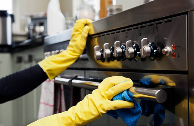 Closeup photograph of two hands cleaning the oven in a domestic kitchen