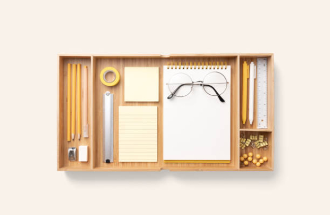Neatly Organized Stationery in Wood Drawer Trays on Beige Colored Background Directly Above View