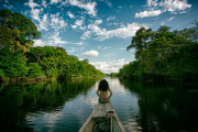 Sailing in a wooden boat on the Amazon river in Peru. An indigenous girl sitting on the front of the boat whilst sailing down the river