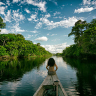 Sailing in a wooden boat on the Amazon river in Peru. An indigenous girl sitting on the front of the boat whilst sailing down the river