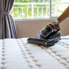 Cropped view of man removing dust on mattress with vacuum cleane