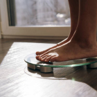 A middle-aged woman standing in the morning on the scales measuring weight. Complexes due to excess weight, self-acceptance. The concept of natural aging, skin care, natural beauty, body positive, anorexia, bulimi