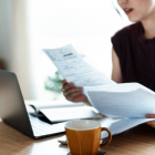 Cropped shot of Asian woman sitting at dining table and working on personal finances using laptop. She handles financial bills, taxes, and expenses from home while creating financial plans and planning budgets.Wealth management, banking and finance concept